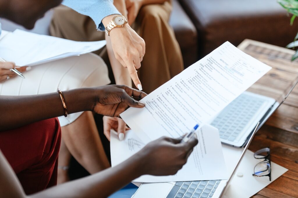 Multiple people gathered around a table, pointing at content strategy documents and discussing content marketing