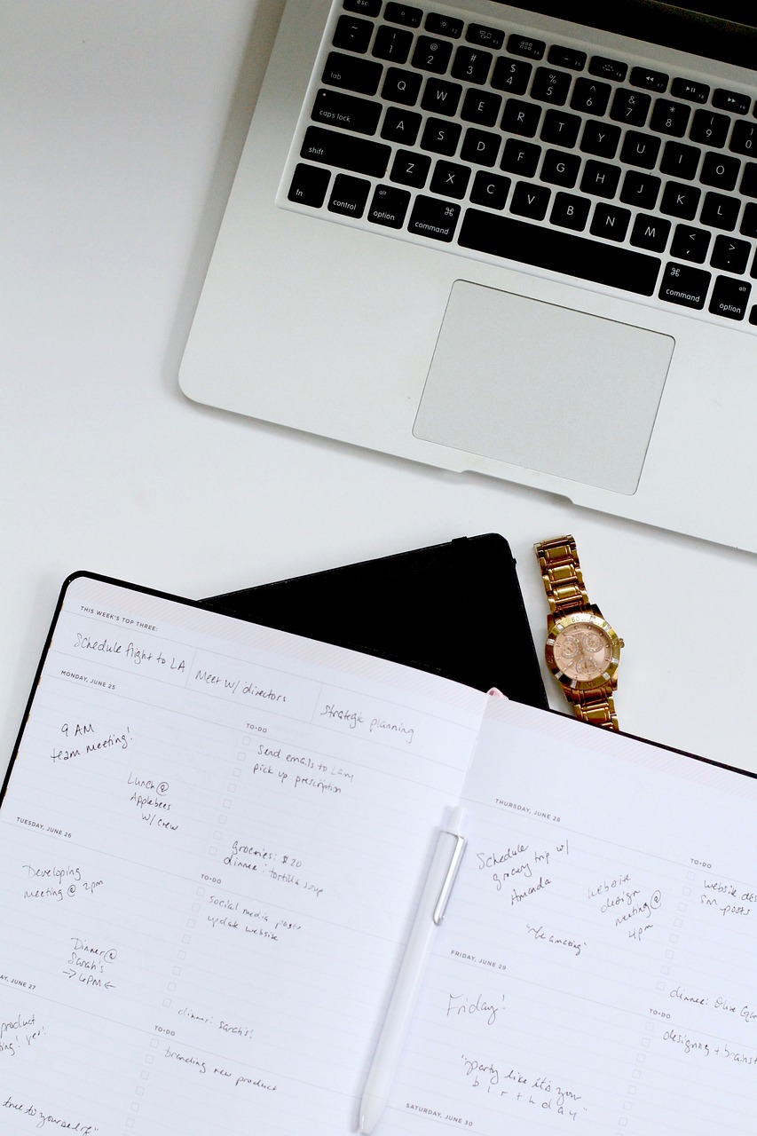 Laptop, planner, and watch on top of a white workspace - ready to do content marketing and content strategy projects